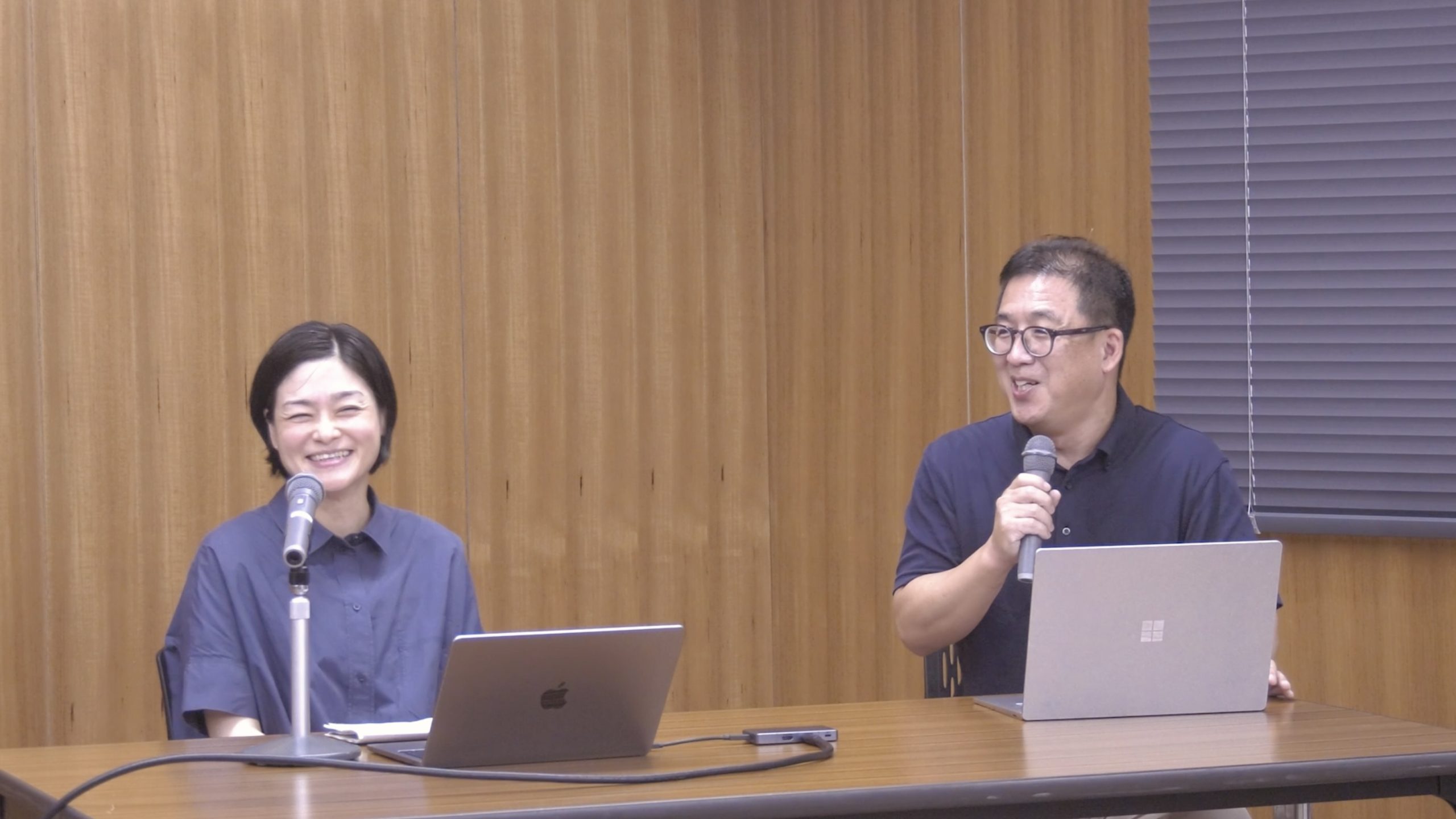 講評を聞く結城准教授と講評を行う村木教授の写真。二人とも笑顔で和やかな雰囲気。