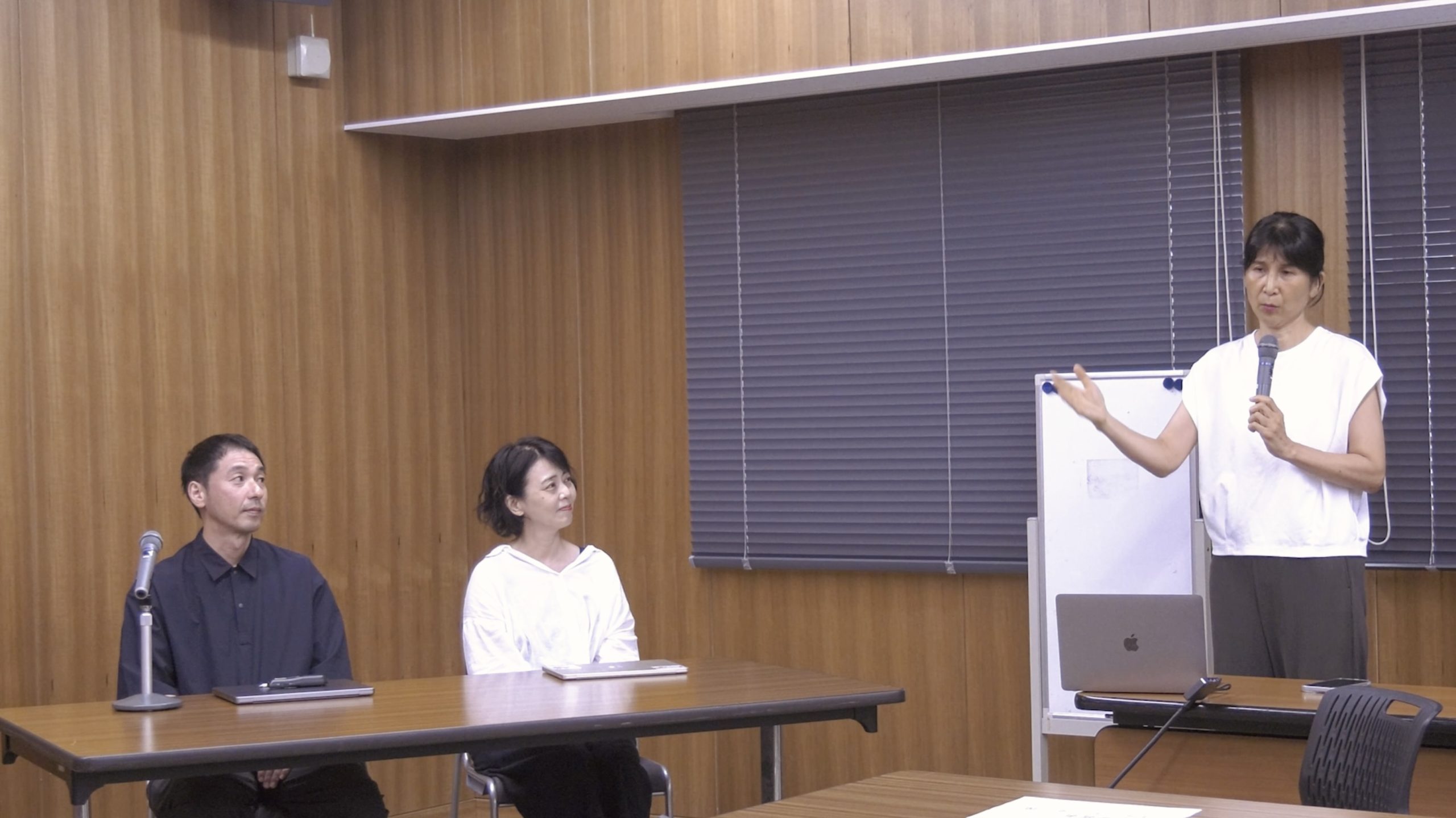 講評を聞く栗山准教授と横谷助教、講評を行う知足教授の写真。和やかな雰囲気。