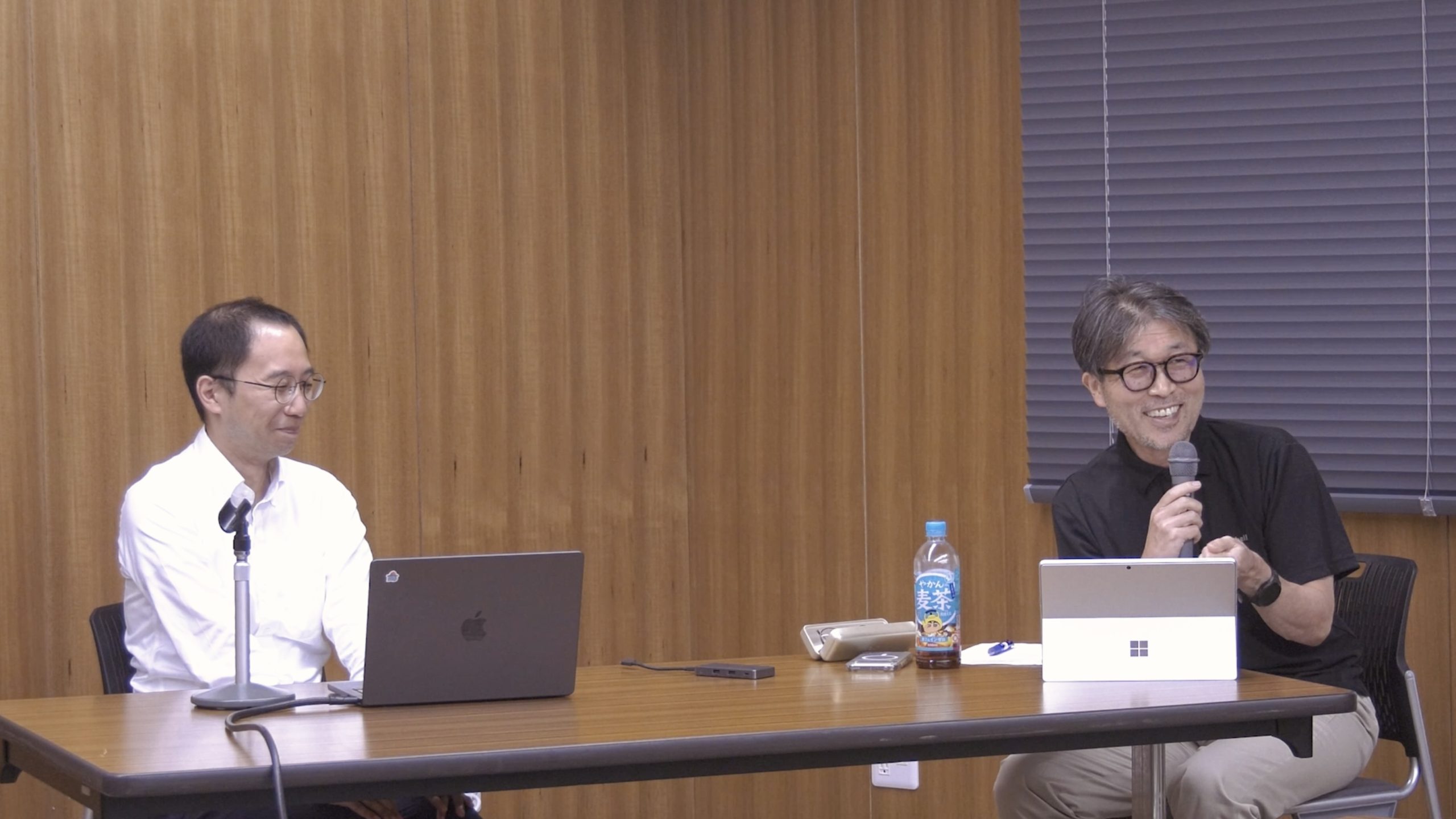 講評を聞く西村助教と講評を行う丸山教授の写真。二人とも笑顔で和やかな雰囲気。